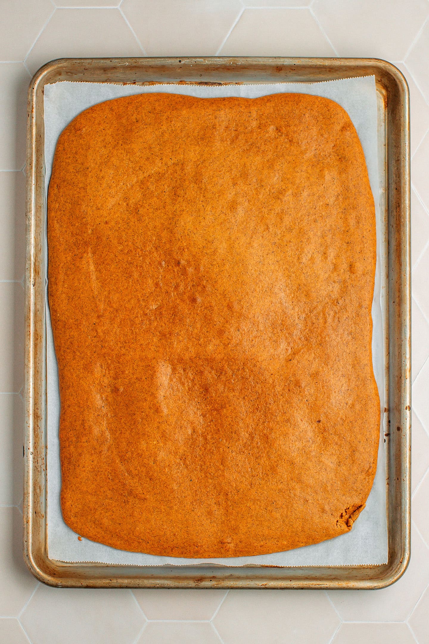 Baked pumpkin sponge cake on a baking sheet.