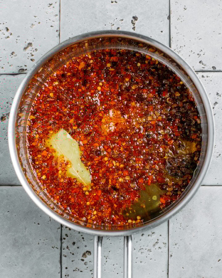 Oil infused with red pepper flakes in a saucepan.