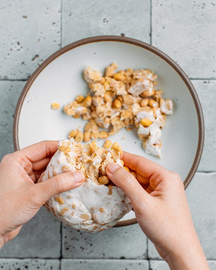 Scrambling a loaf of tempeh into small pieces.