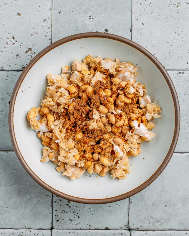 Scrambled tofu, soy sauce, sesame oil, and five-spice powder in a mixing bowl.