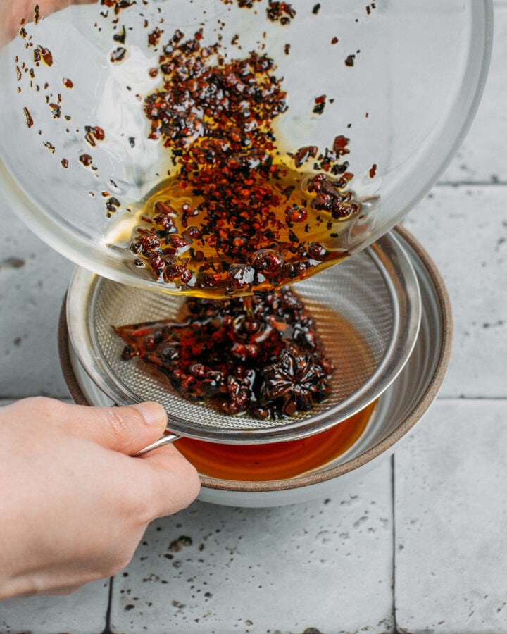 Straining chili oil using a fine-sieve mesh.
