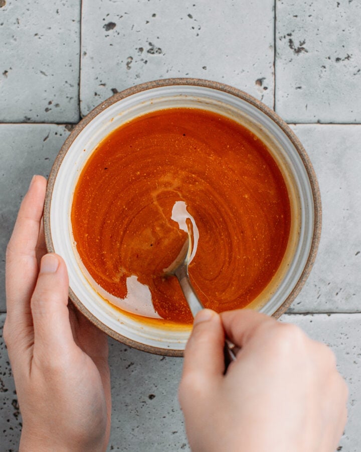Stirring a sauce made with chili oil and sesame paste in a small bowl.