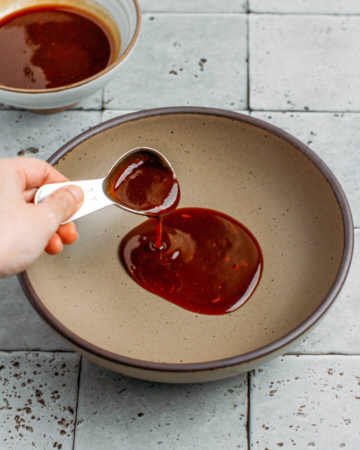 Pouring sauce into a brown bowl.