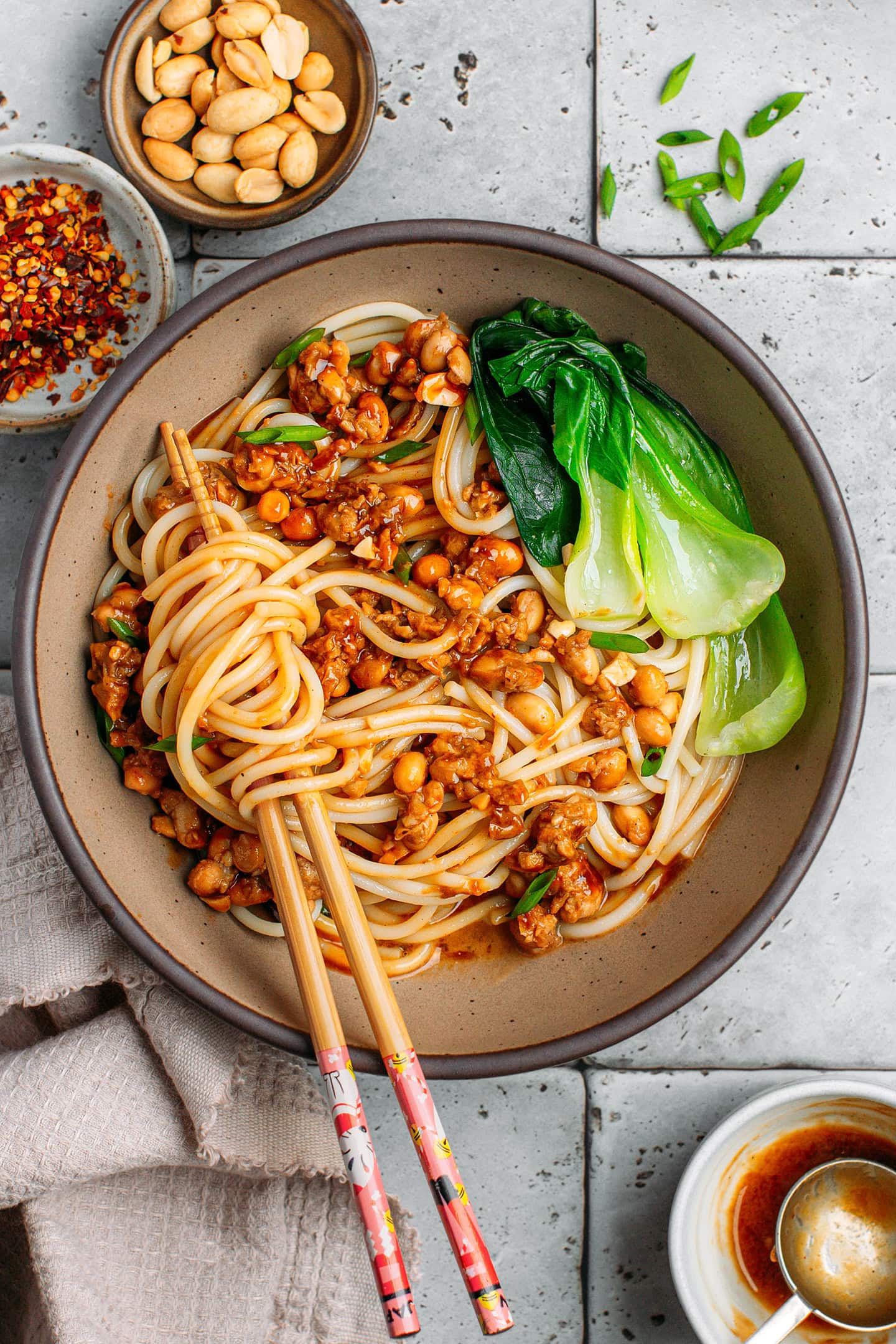 Vegan Dan Dan noodles with scrambled tempeh, roasted peanuts, and pak choy in a bowl.
