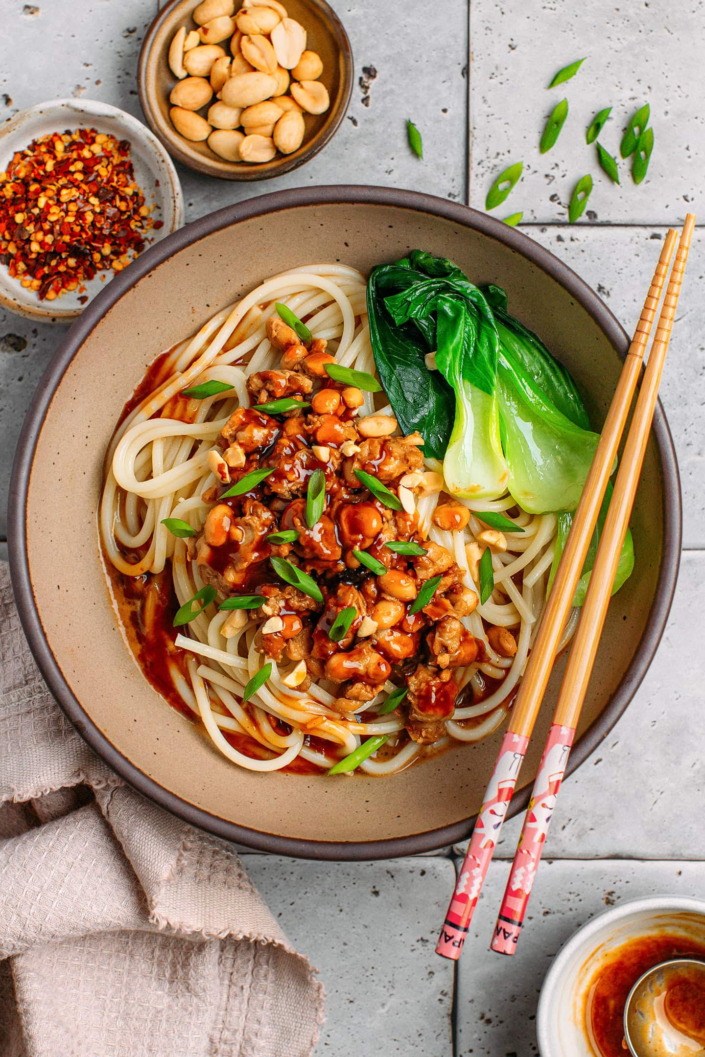 Ceramic bowl filled with Sichuan sauce, noodles, tempeh scramble, and pak choy.