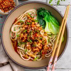 Dan dan noodles topped with tempeh scramble in a bowl.