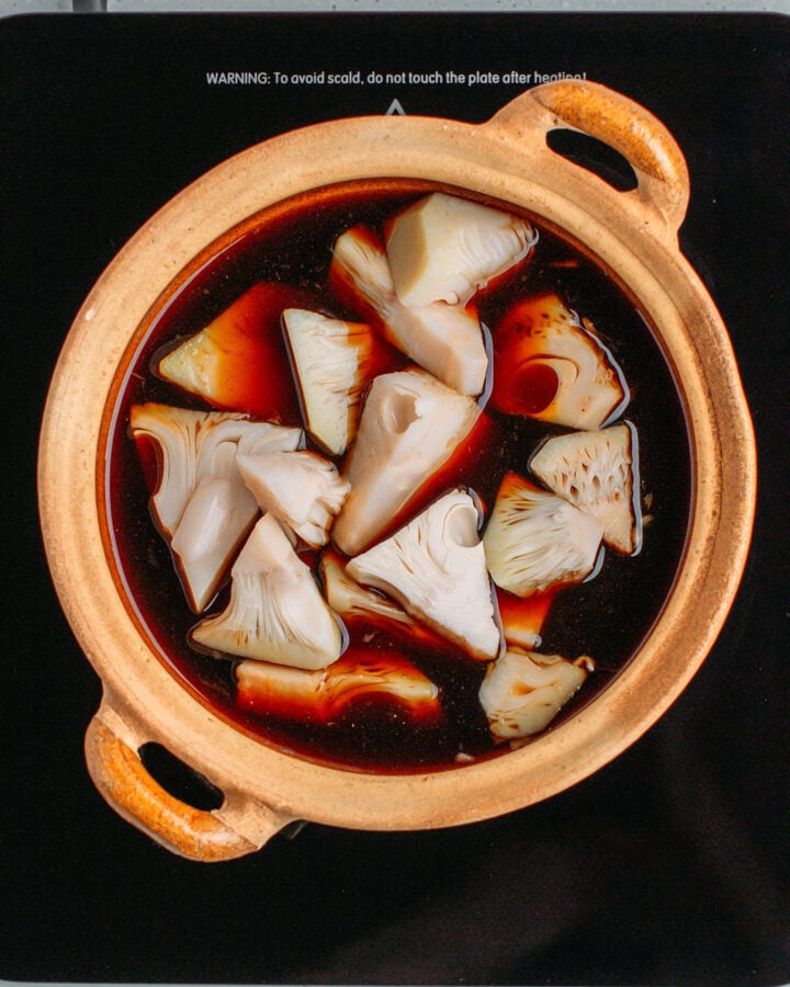 Chunks of jackfruit with a sweet and salty sauce in a clay pot.