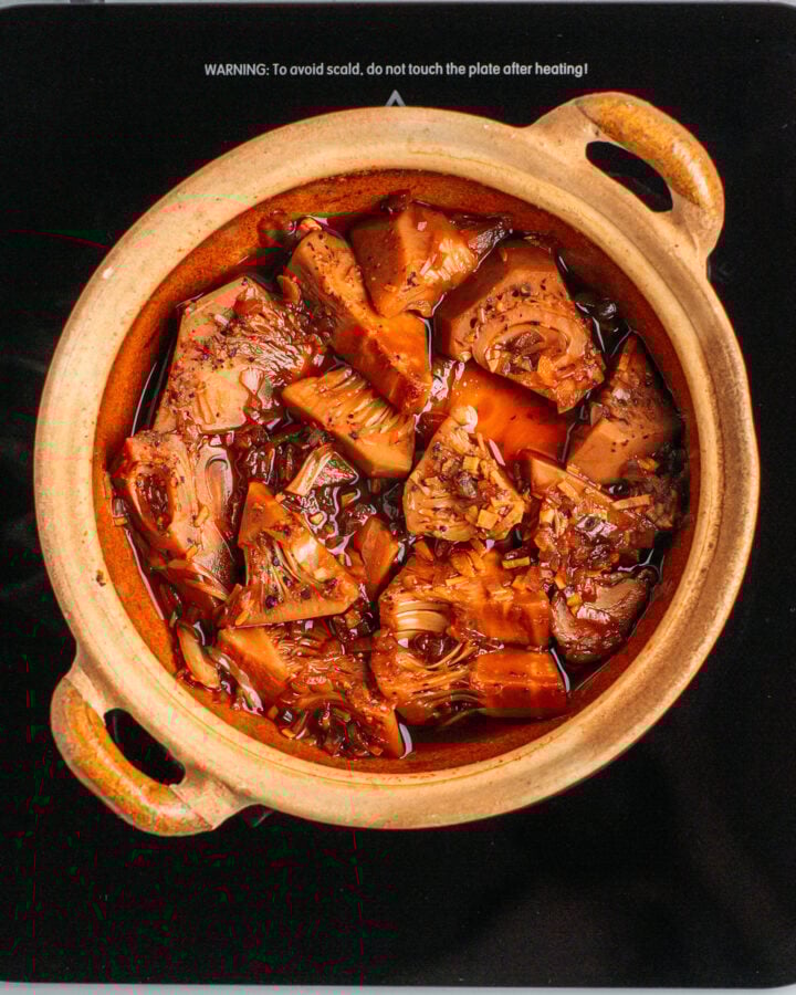 Young jackfruit simmered in a sweet and salty sauce inside a clay pot.