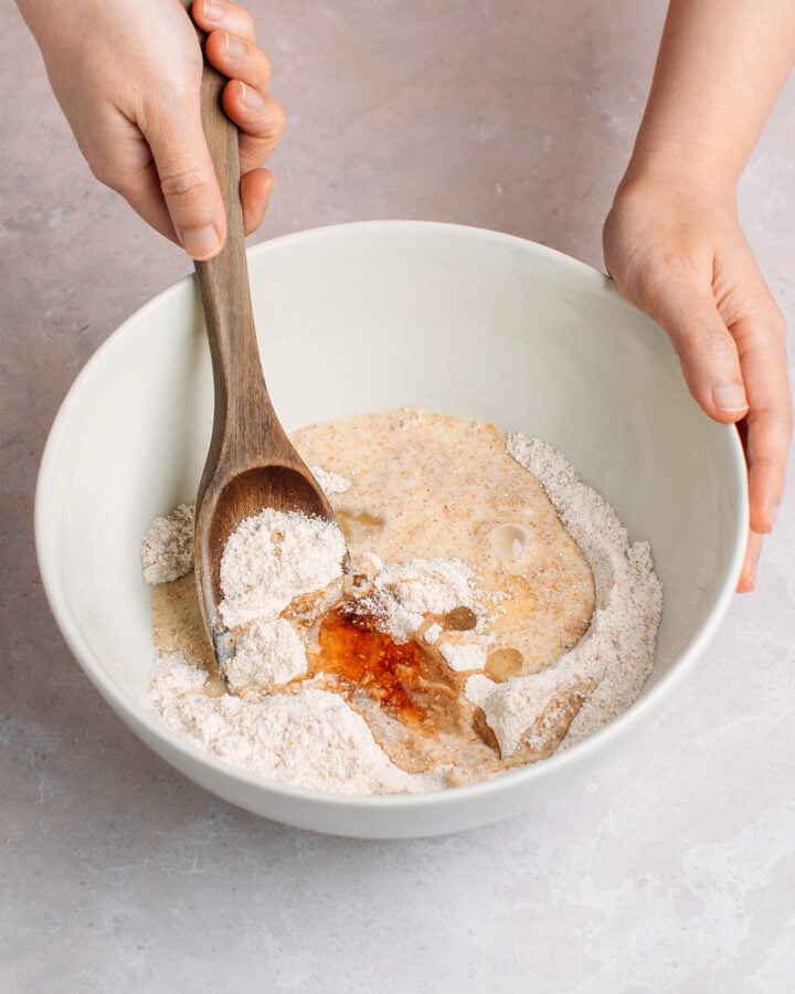 Stirring milk, flour, corn flour, and vanilla extract in a mixing bowl.