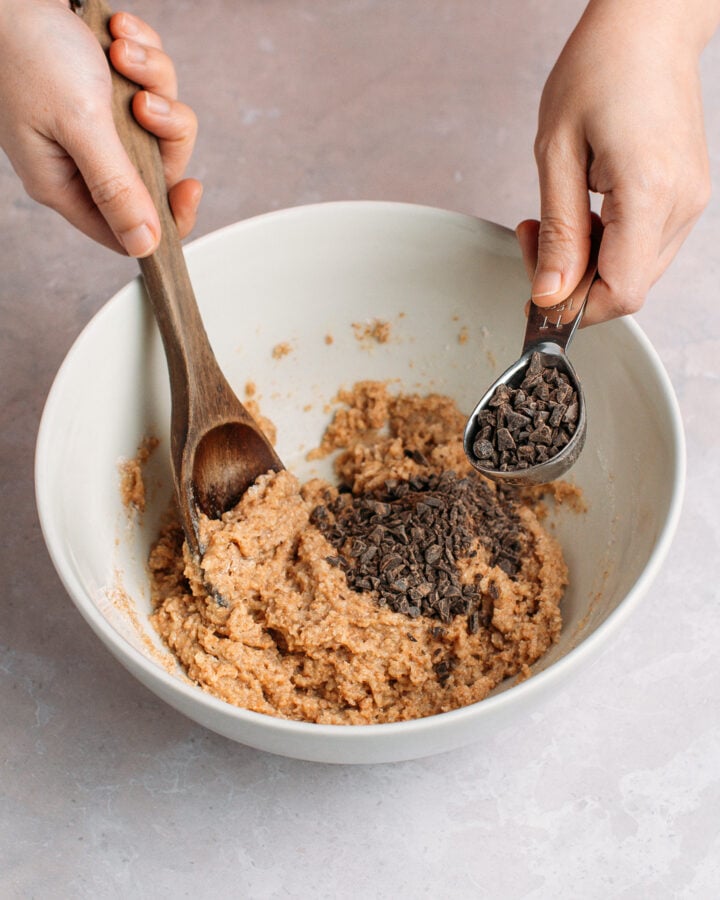 Adding chopped chocolate to a batter in a mixing bowl.