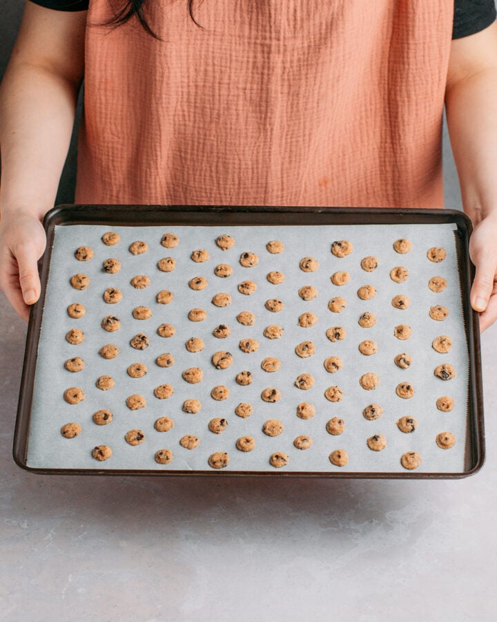 Holding a baking sheet filled with unbaked mini cookie cereal.