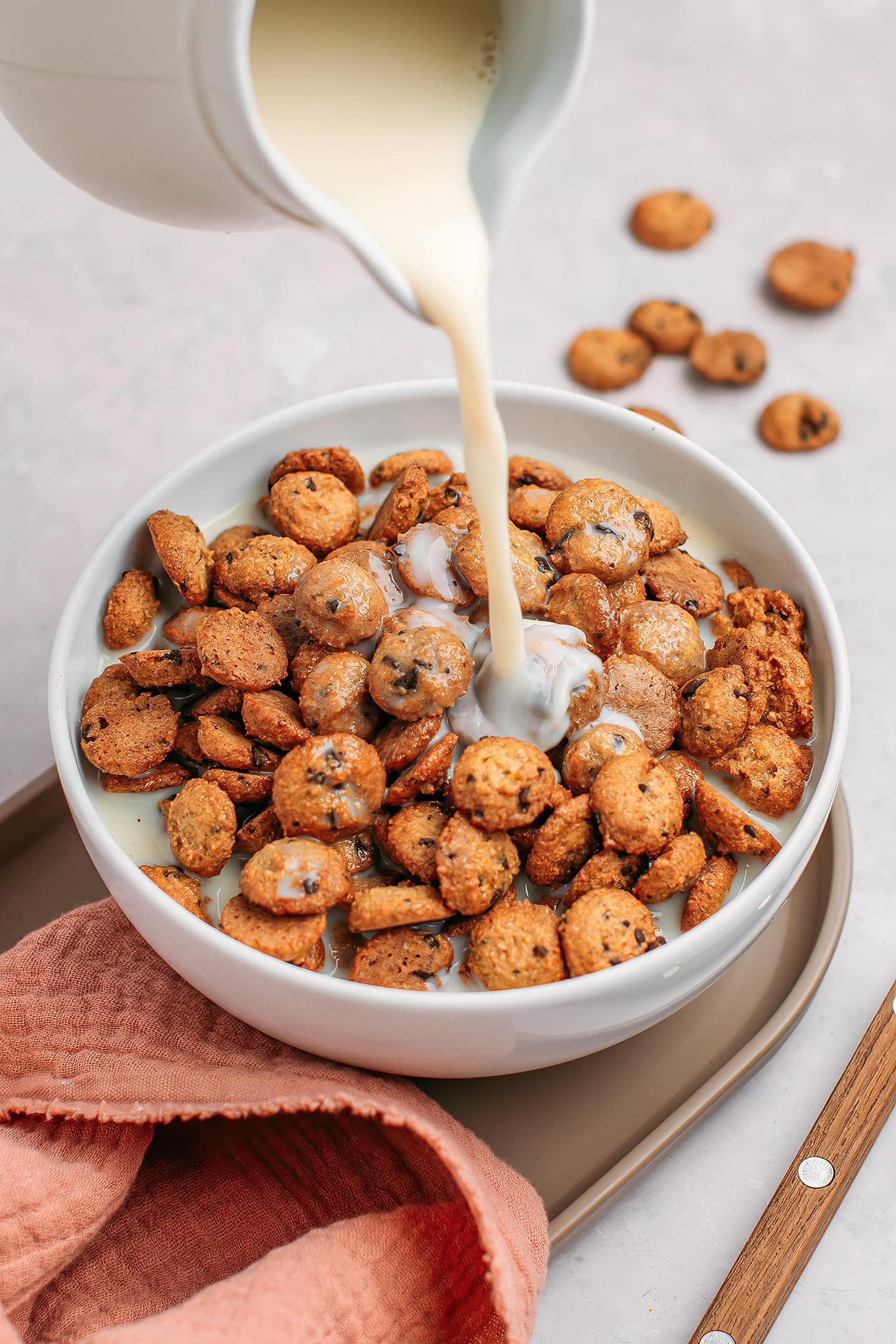 Pouring milk into a bowl containing cookie crisp cereal.