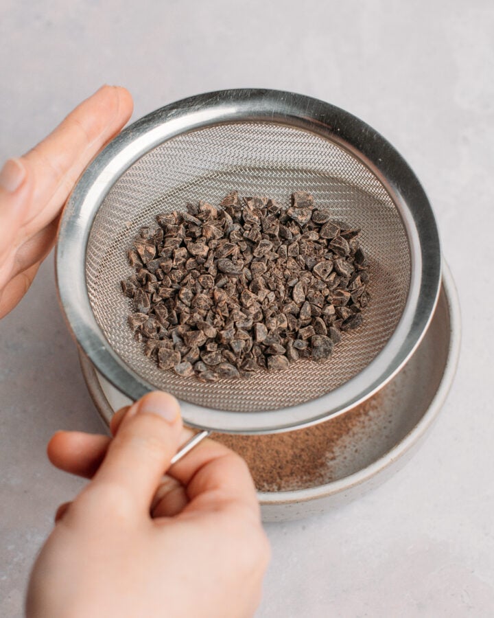 Using a fine-mesh sieve to remove chocolate powder from chopped chocolate chips.