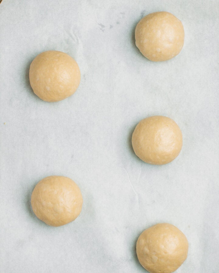 Five balls of dough on a baking sheet.