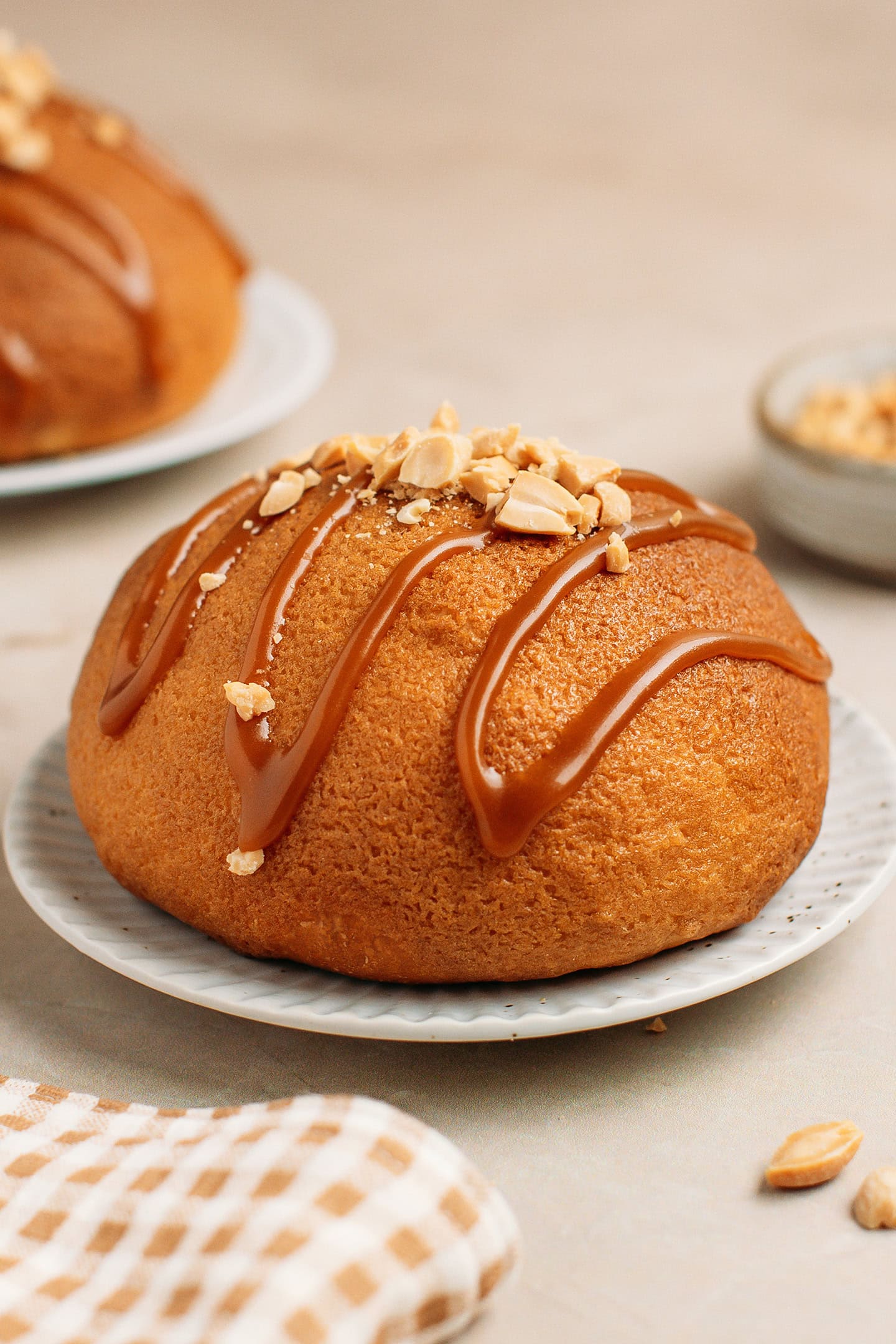 Vegan Papparoti bun drizzled with caramel sauce and topped with crushed peanuts.
