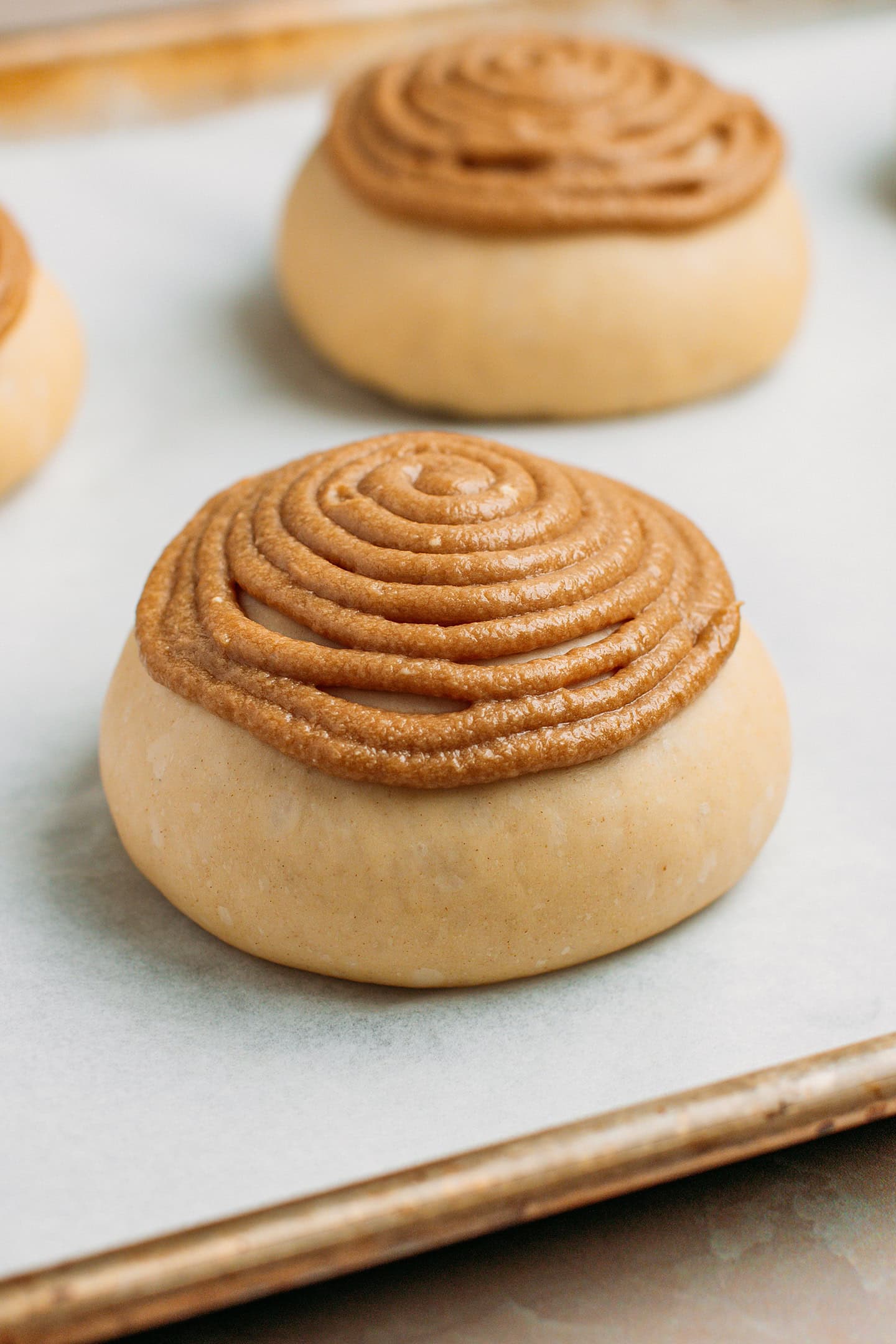 Brioche bun topped with coffee craquelin on a baking sheet.