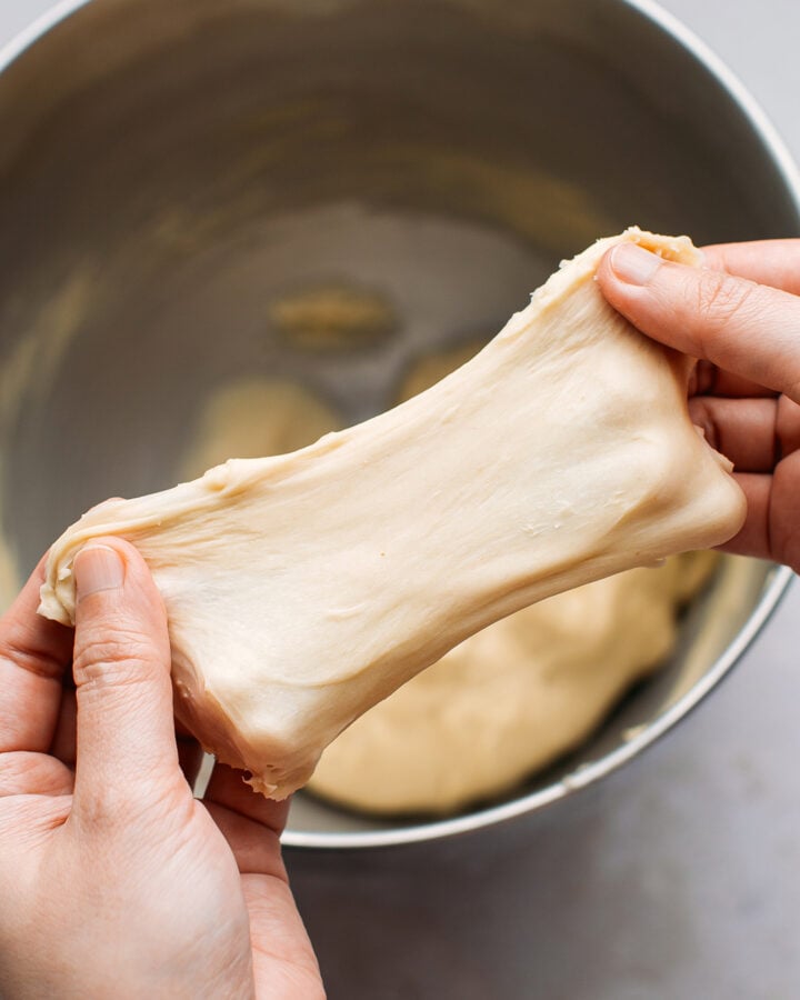Stretching a ball of dough to show how it passes the windowpane test.