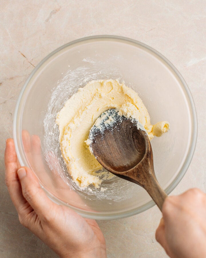Creaming butter with sugar in a small glass bowl.
