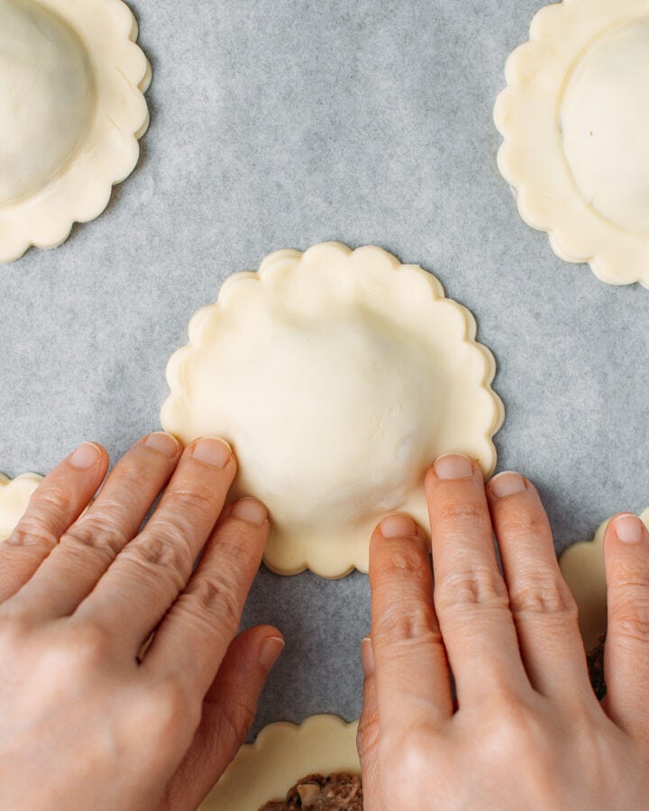 Pressing the edges of a vegan meat pie to seal it.