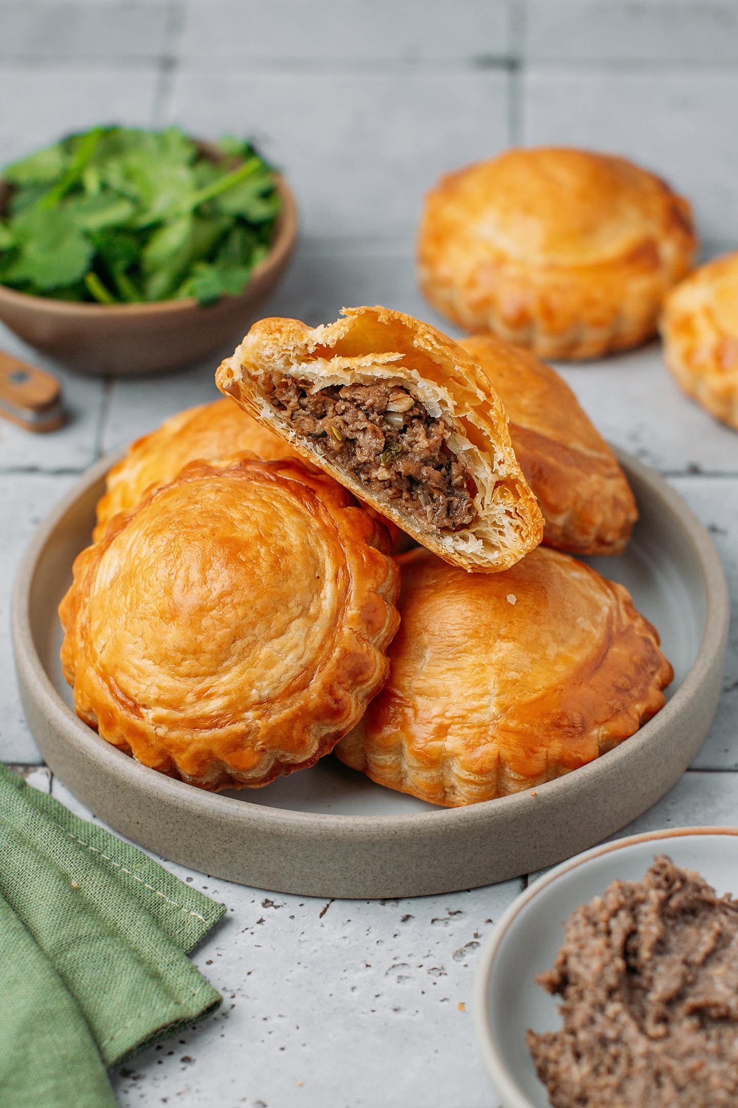 Five vegan meat pastries on a small ceramic plate.