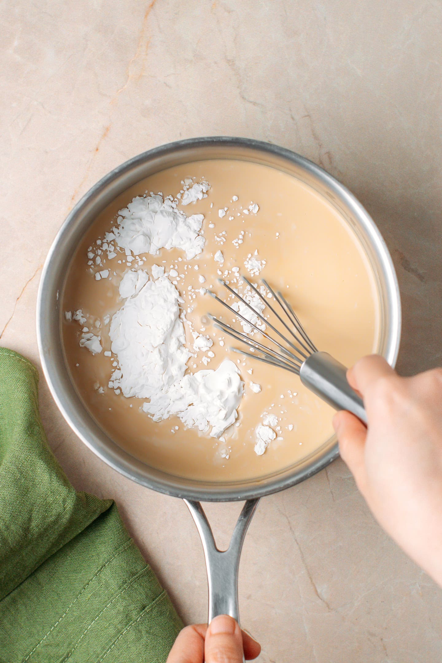 Whisking sweet rice flour with peanut milk in a saucepan.