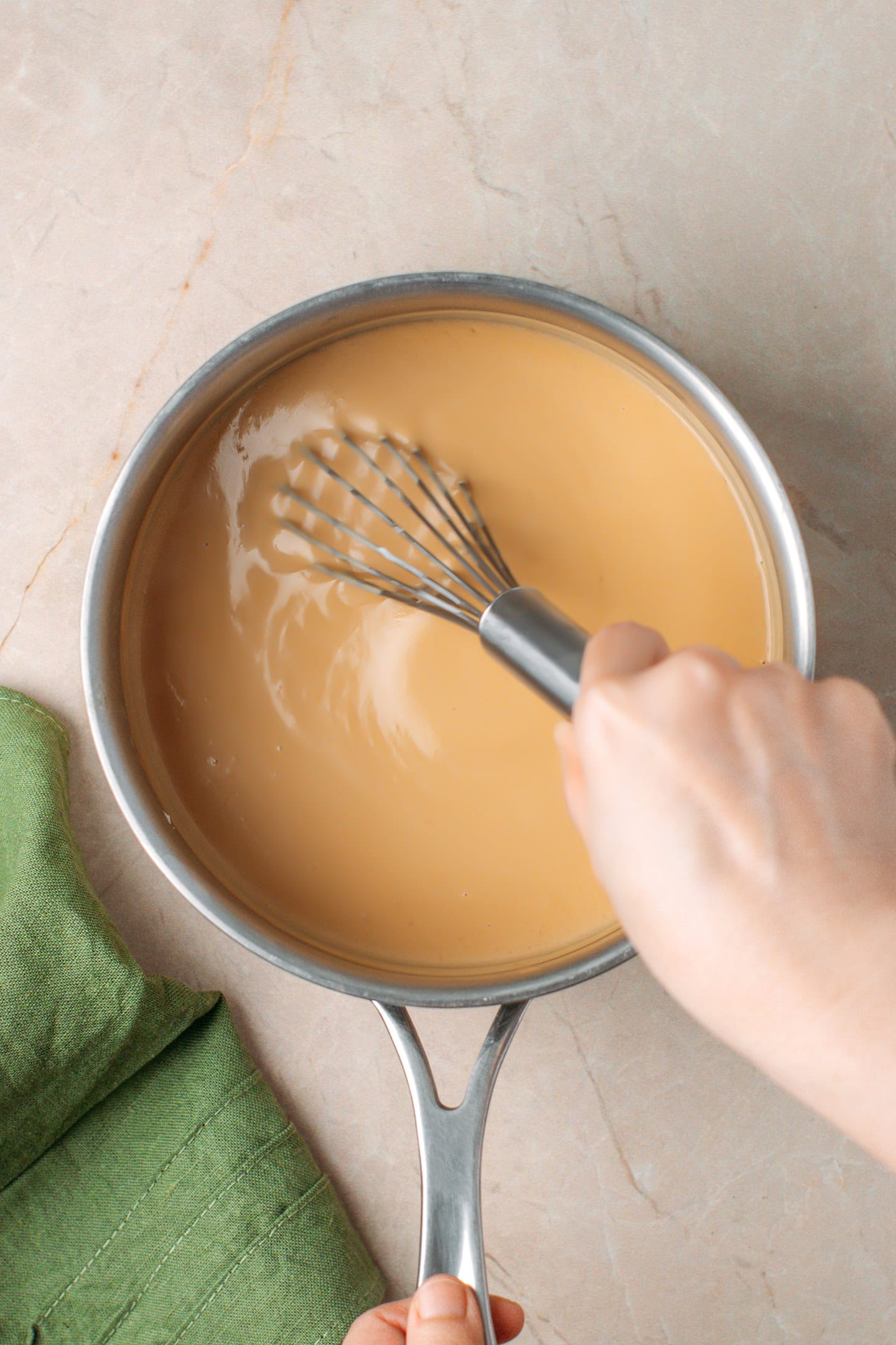 Whisking peanut milk in a saucepan until it thickens.