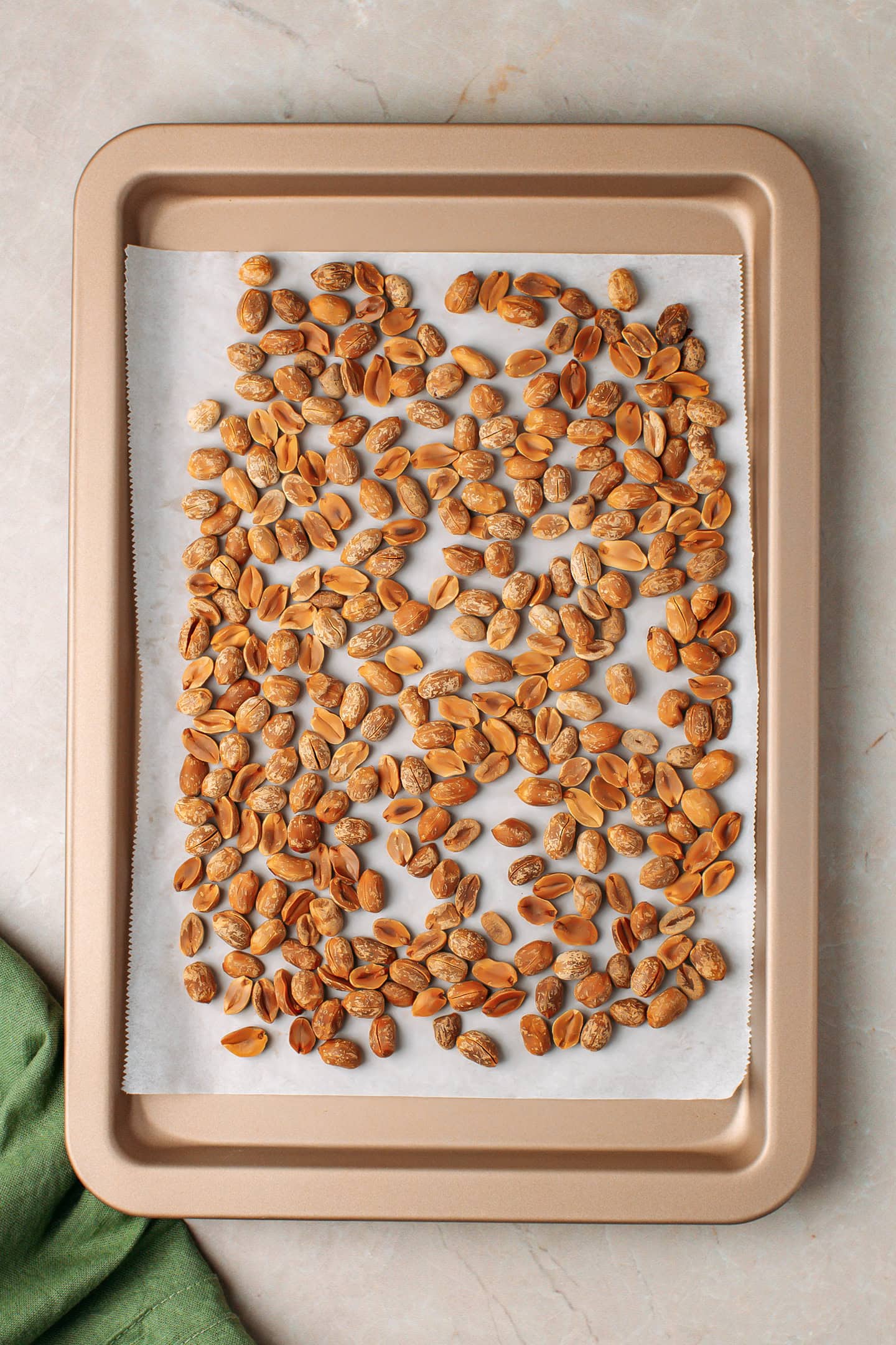 Roasted peanuts arranged on a baking sheet.