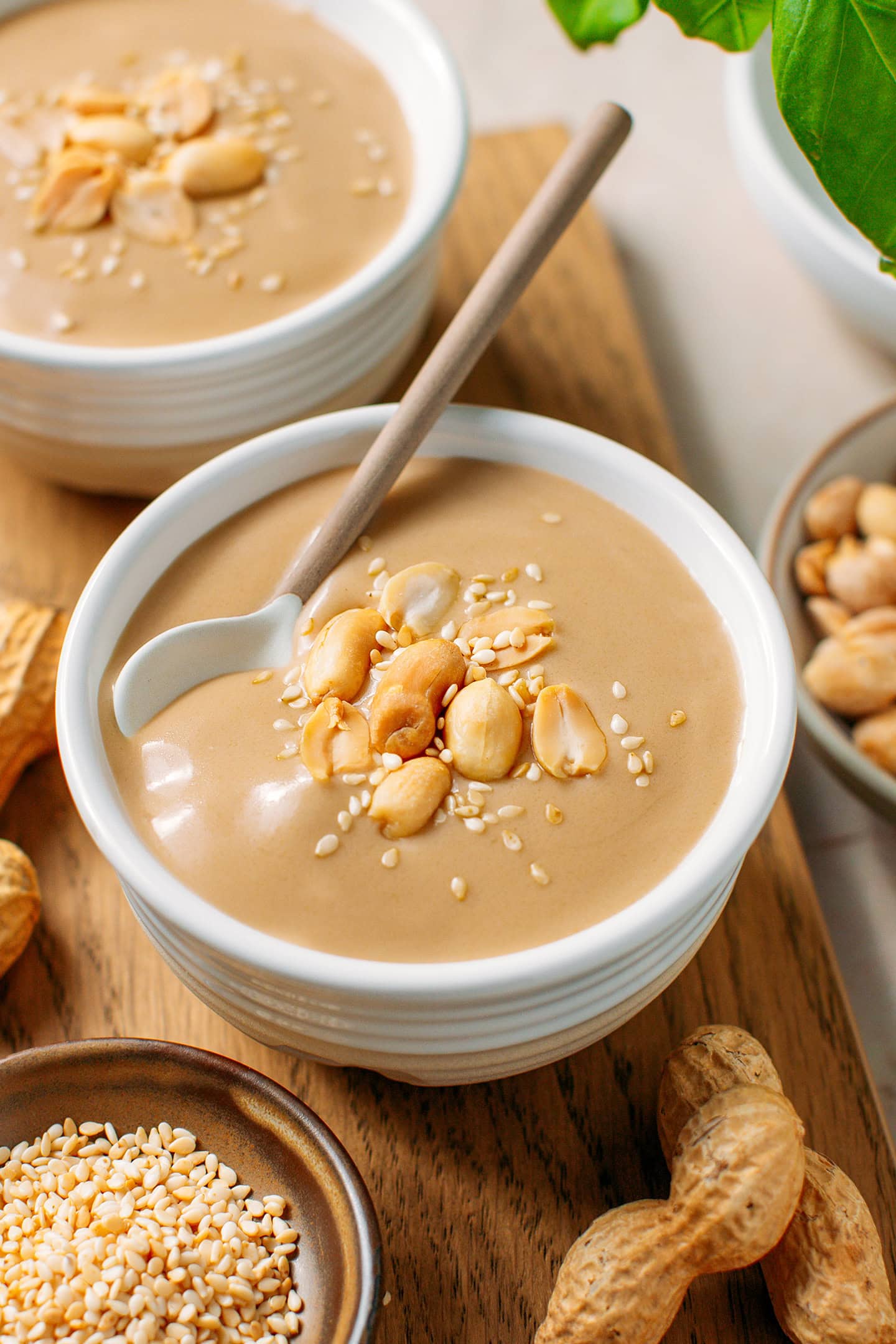 Small bowl of peanut soup garnished with roasted peanuts and toasted sesame seeds.