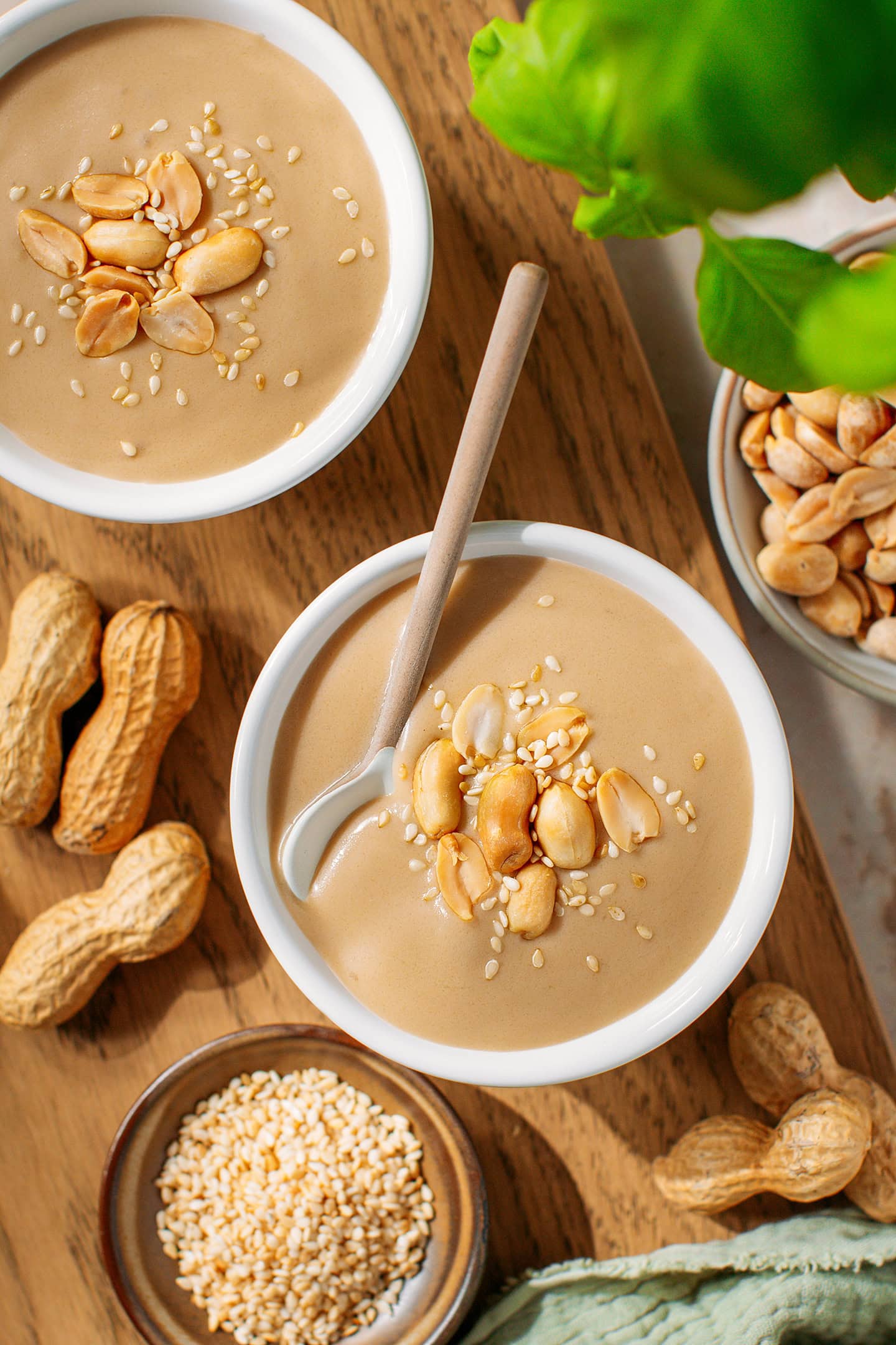Two bowls filled with sweet peanut soup and garnished with roasted peanuts and sesame seeds.