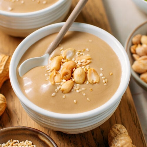 Small bowl filled with sweet peanut soup and topped with roasted peanuts and sesame seeds.