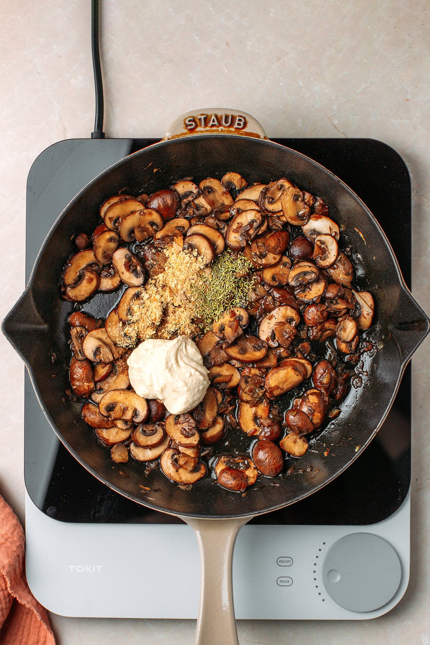 Sautéed mushrooms, rosemary, nutritional yeast, and hummus in a skillet.