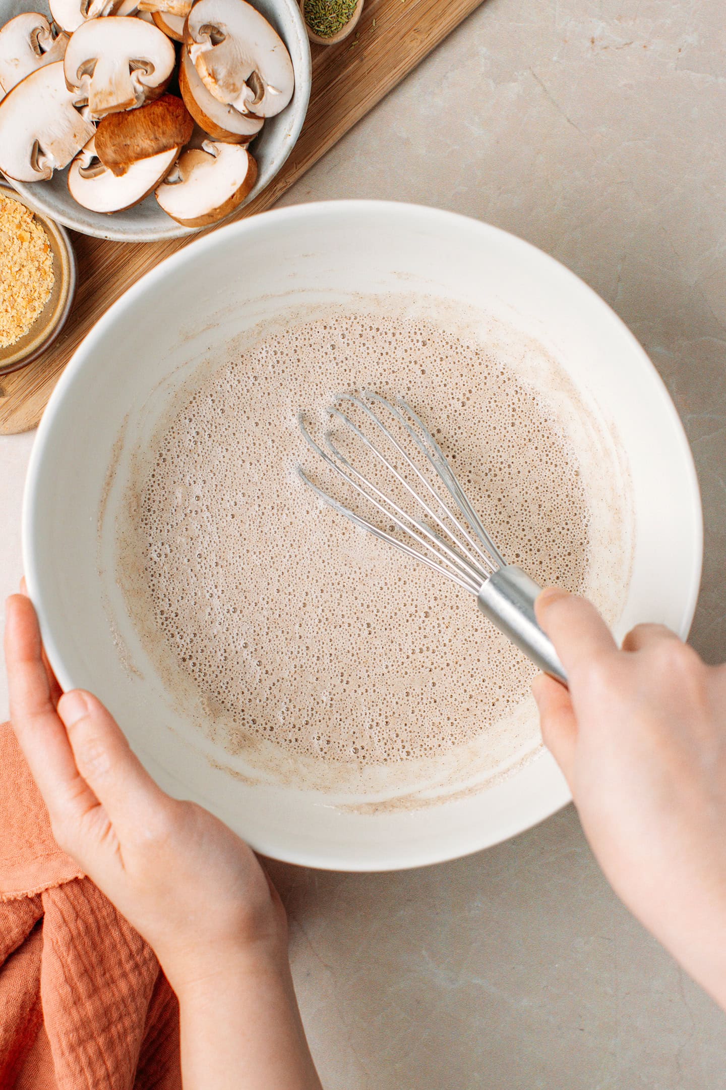 Whisking a buckwheat crêpe batter in a mixing bowl.