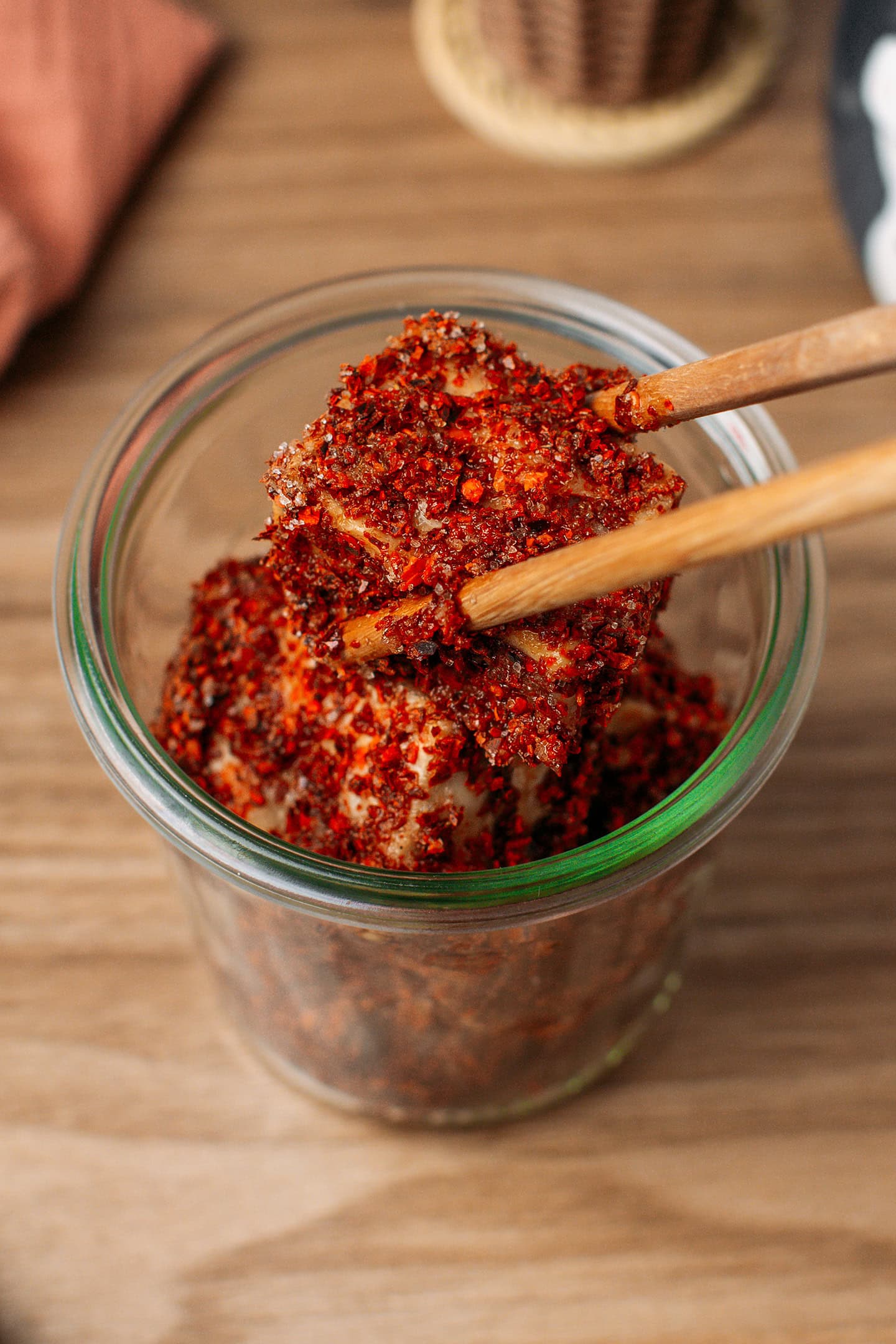 Placing tofu coated with chili flakes into a glass jar.
