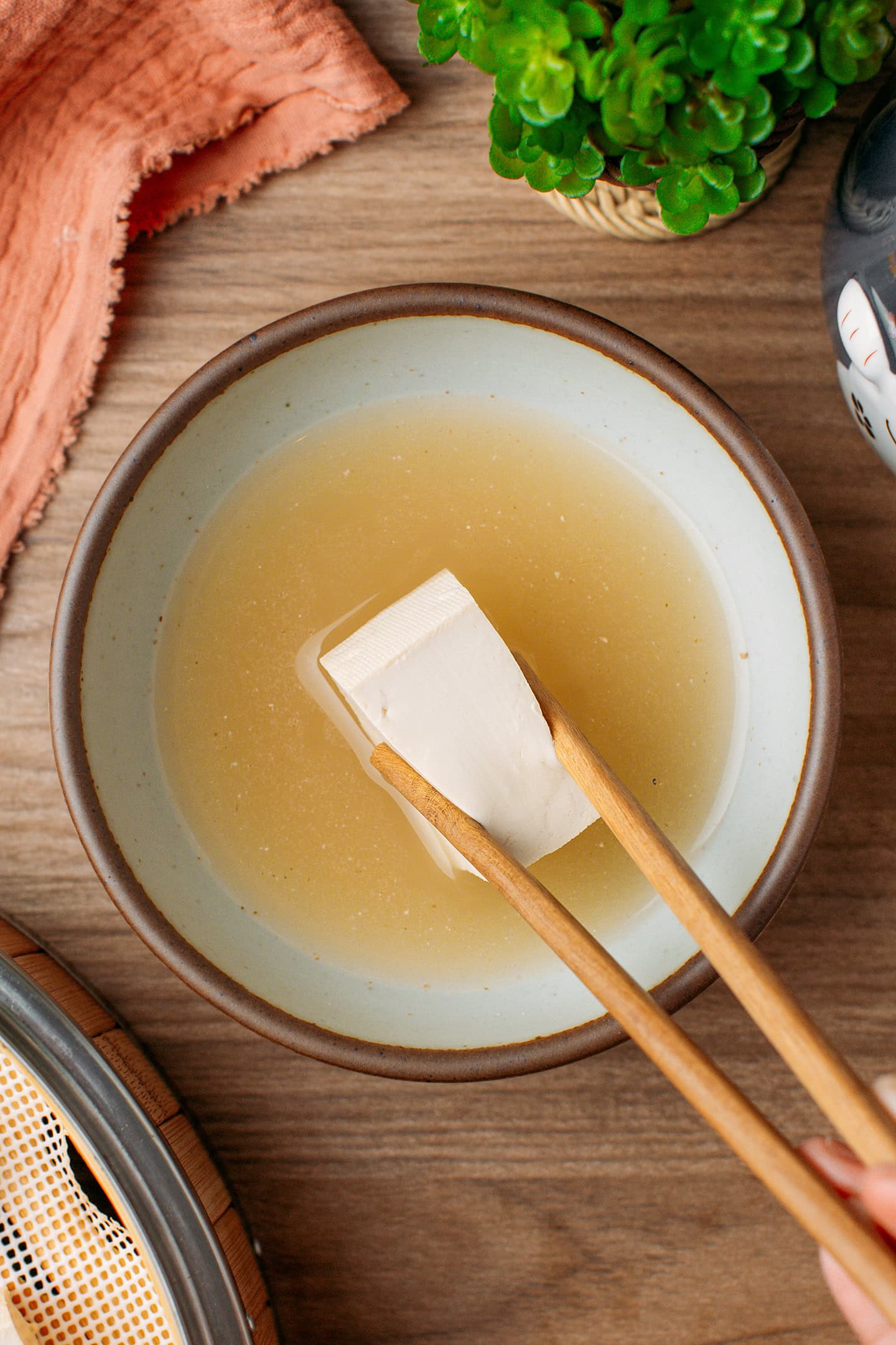 Dipping a cube of tofu into a mix of water and starter cultures.