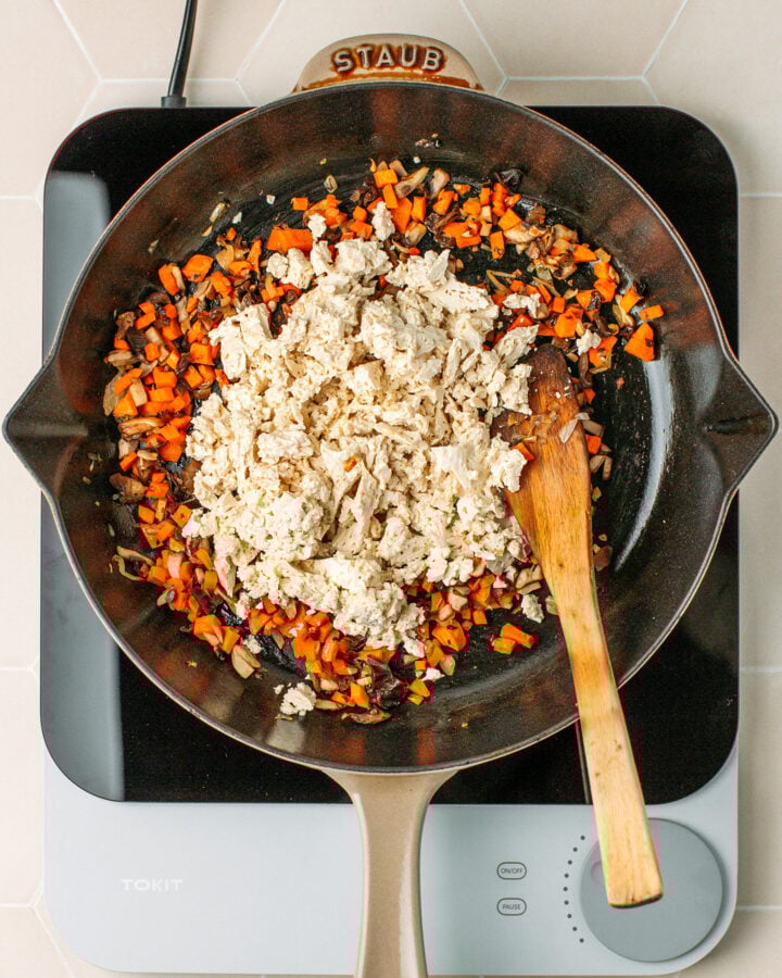 Sautéed carrots, mushrooms, and scrambled tofu in a skillet.