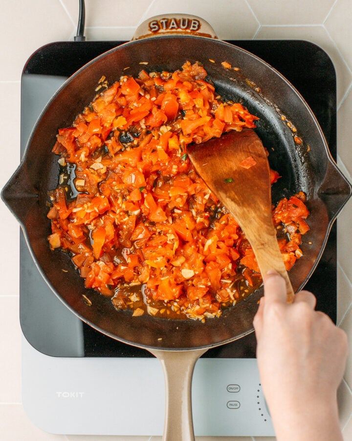 Stirring cooked diced tomatoes in a skillet.