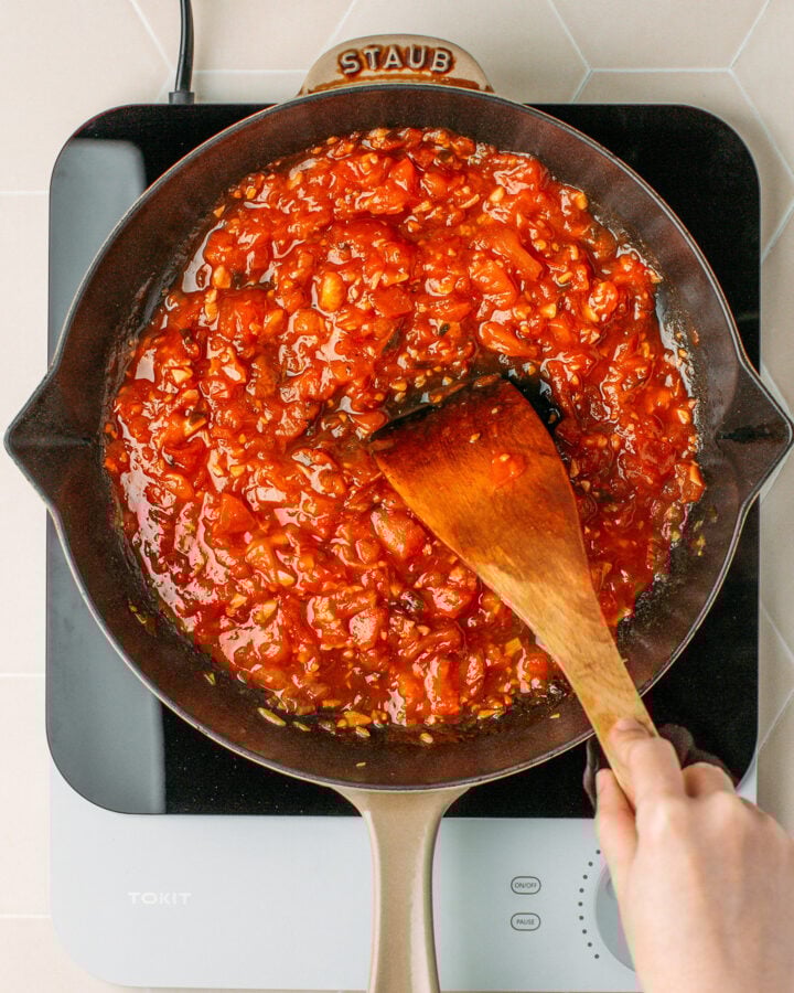 Stirring cooked tomato sauce in a skillet.