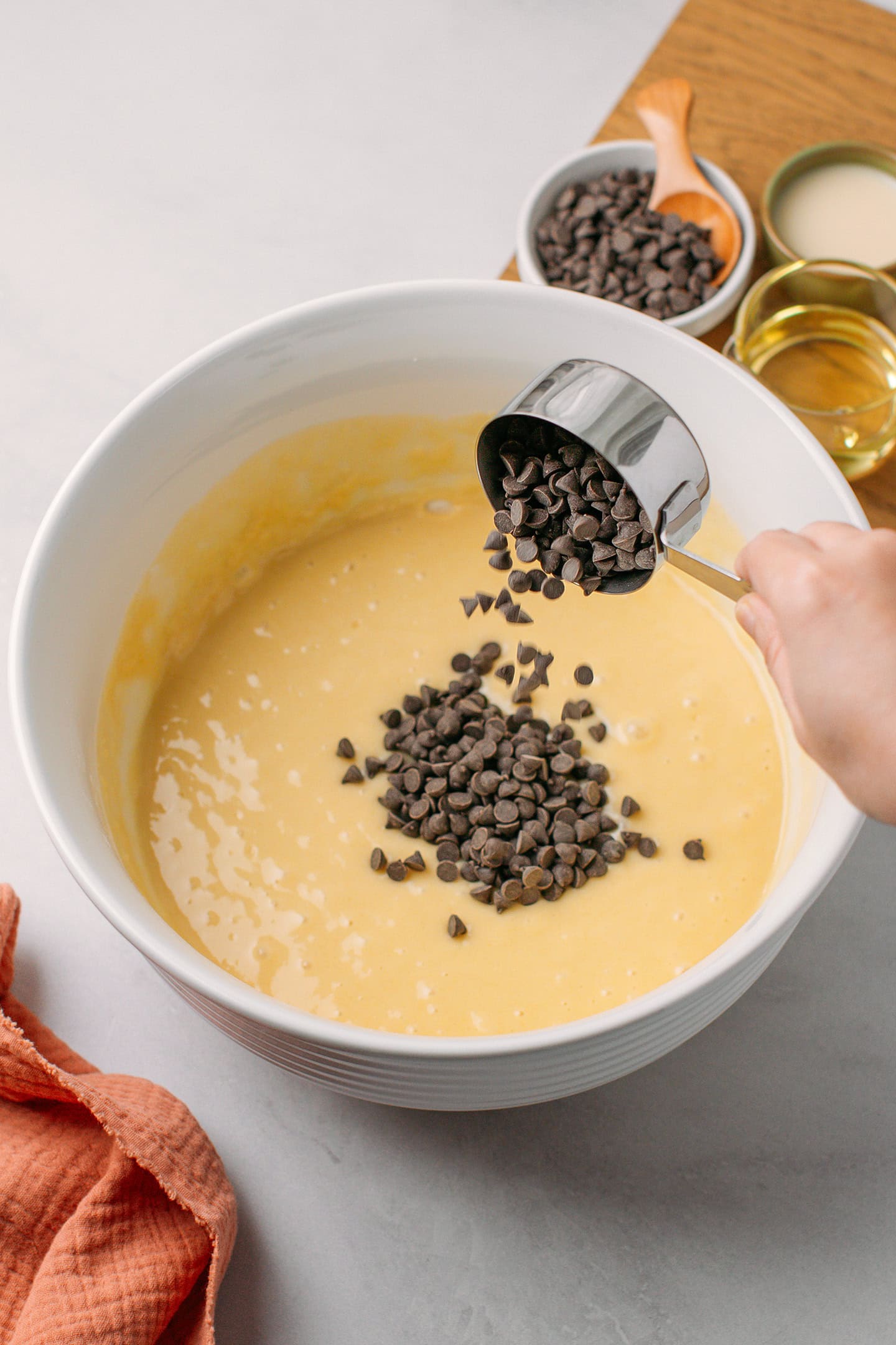 Pouring dark chocolate chips into a bowl containing a cake batter.