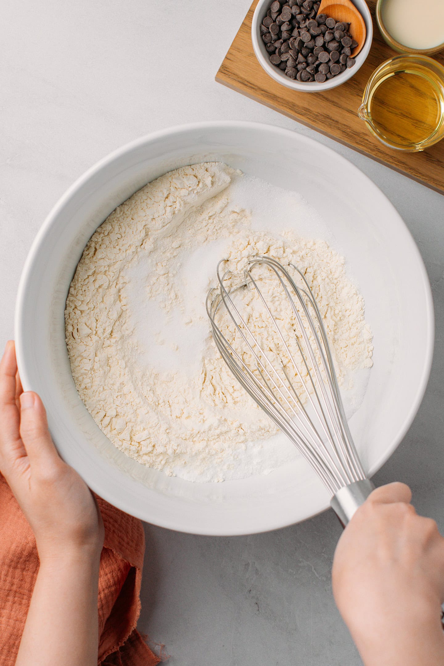 Whisking flour with sugar in a mixing bowl.