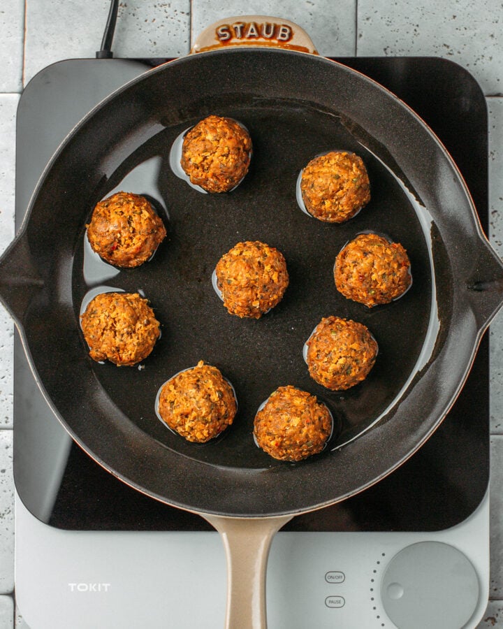 Nine vegan meatballs in a skillet.