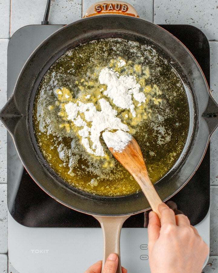 Stirring flour with melted butter in a skillet.