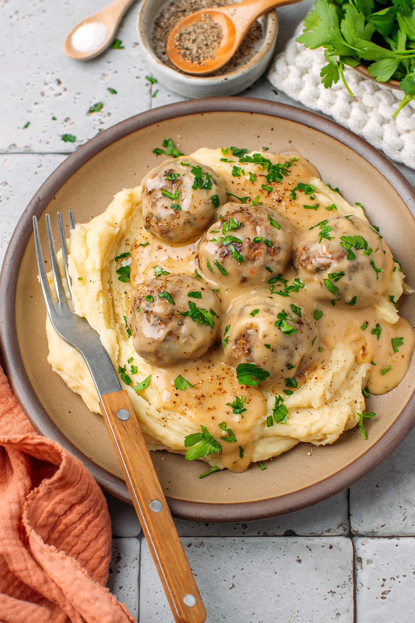 Five meatballs topped with chopped parsley and served in a gravy over mashed potatoes.