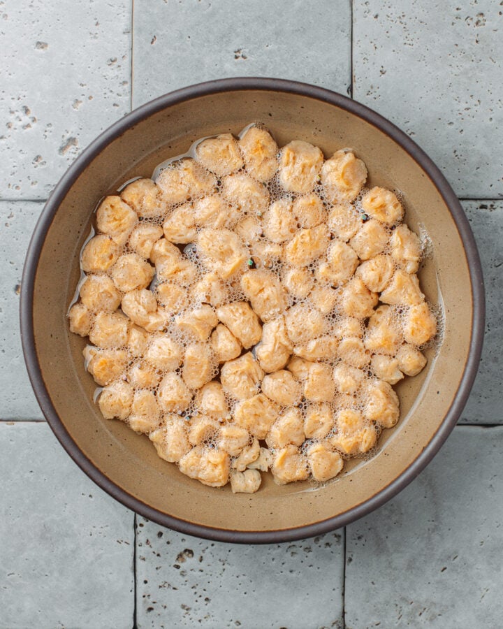 TVP soy chunks rehydrating in a bowl of water.
