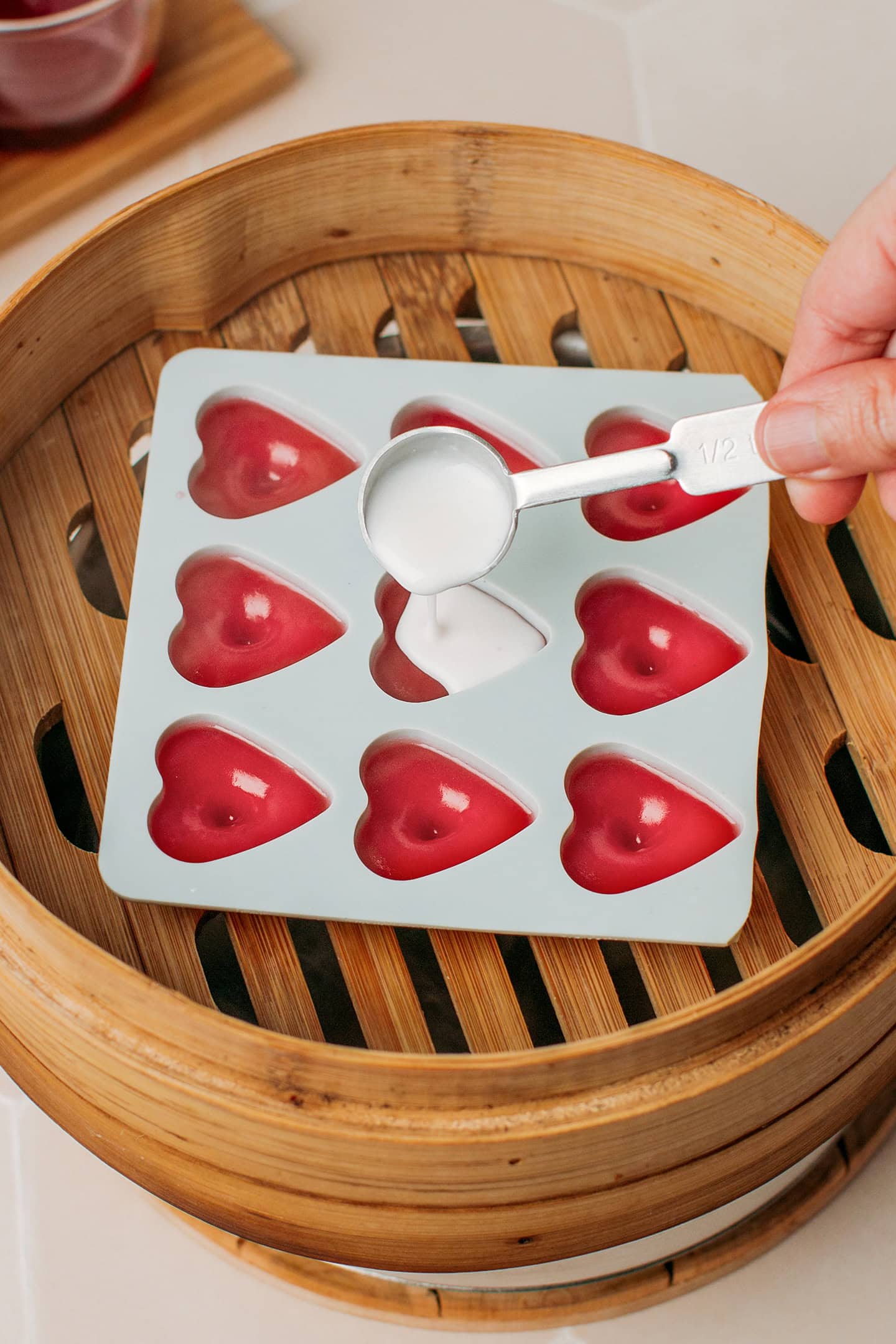 Pouring a white batter into a silicone heart-shaped mold.