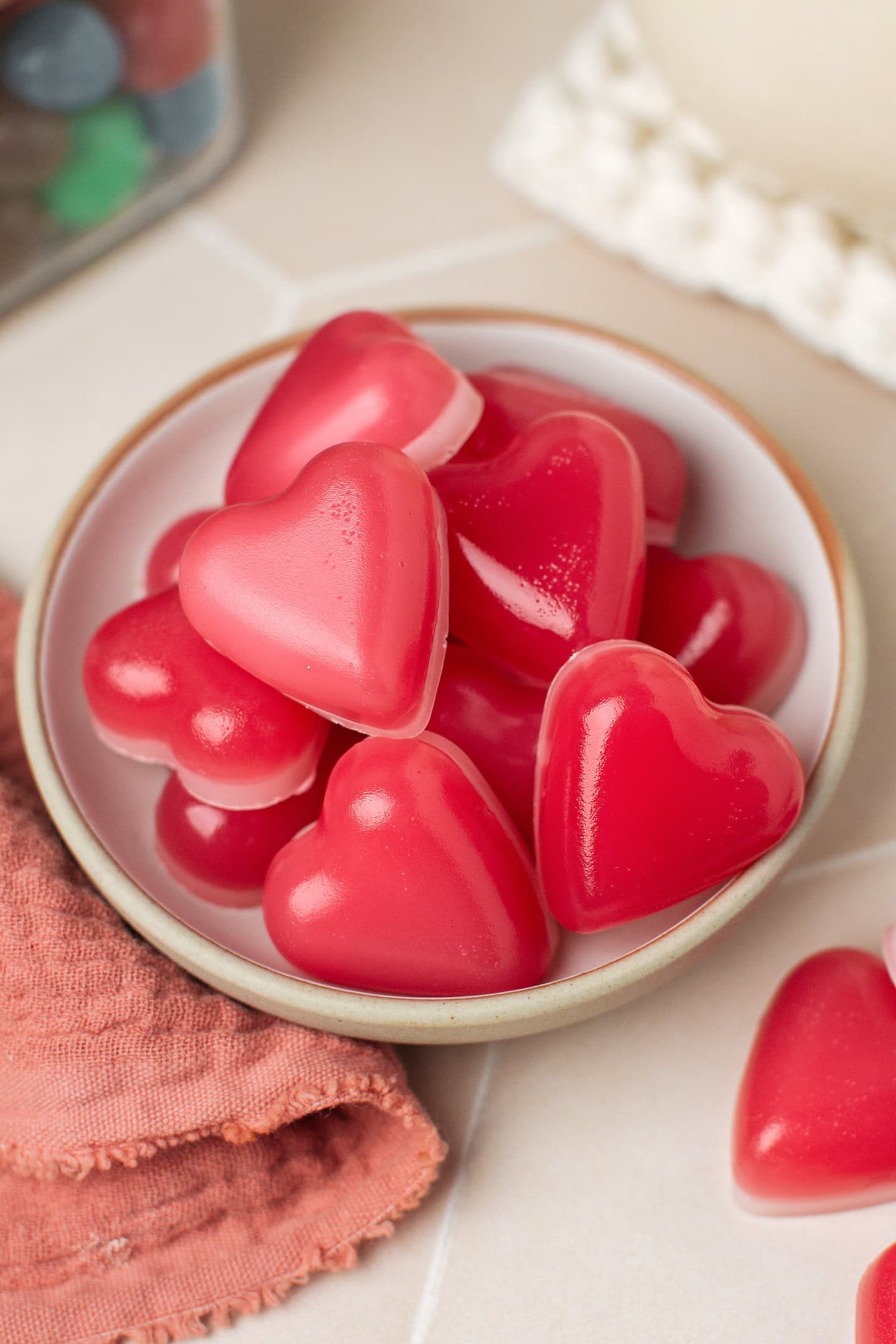 Heart-shaped red gummies in a small white plate.