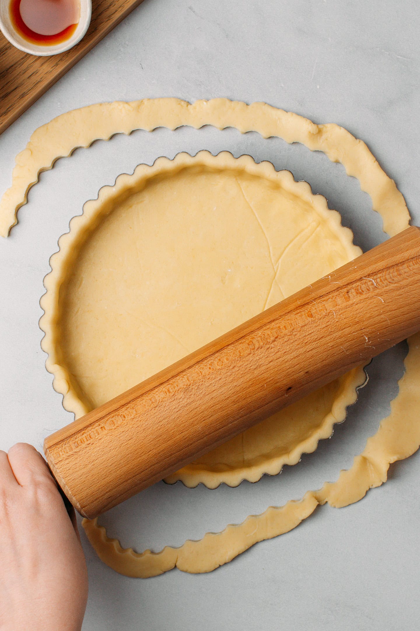 Using a rolling pin to cut off the excess dough in a pie pan.