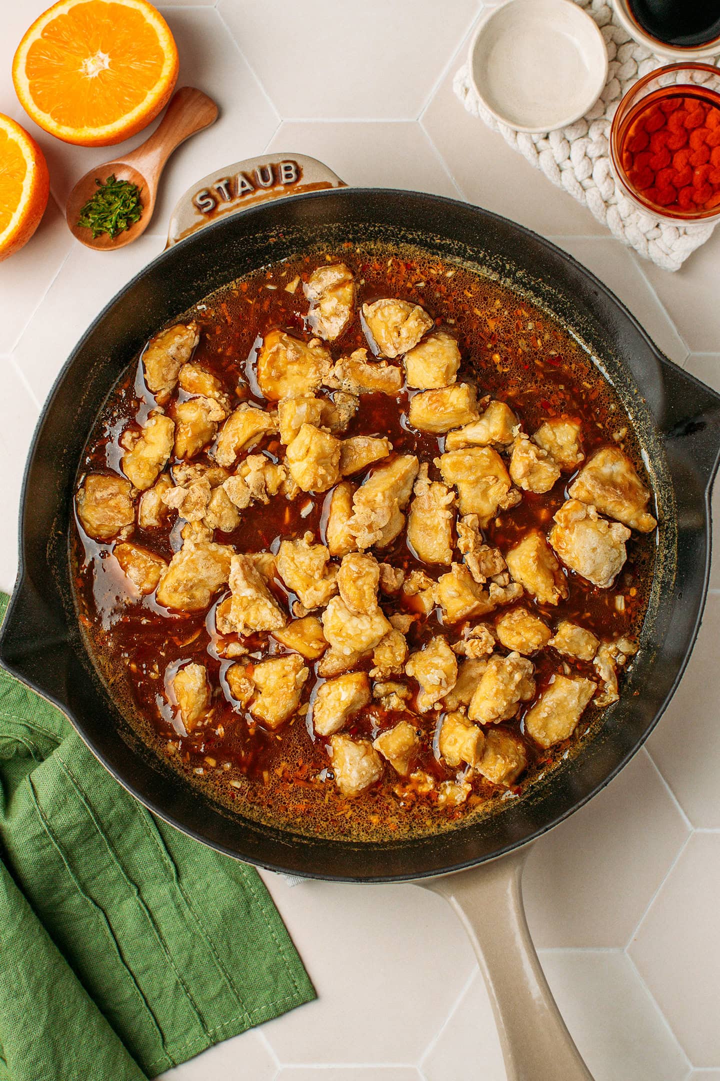 Orange sauce and golden-brown tofu pieces in a skillet.