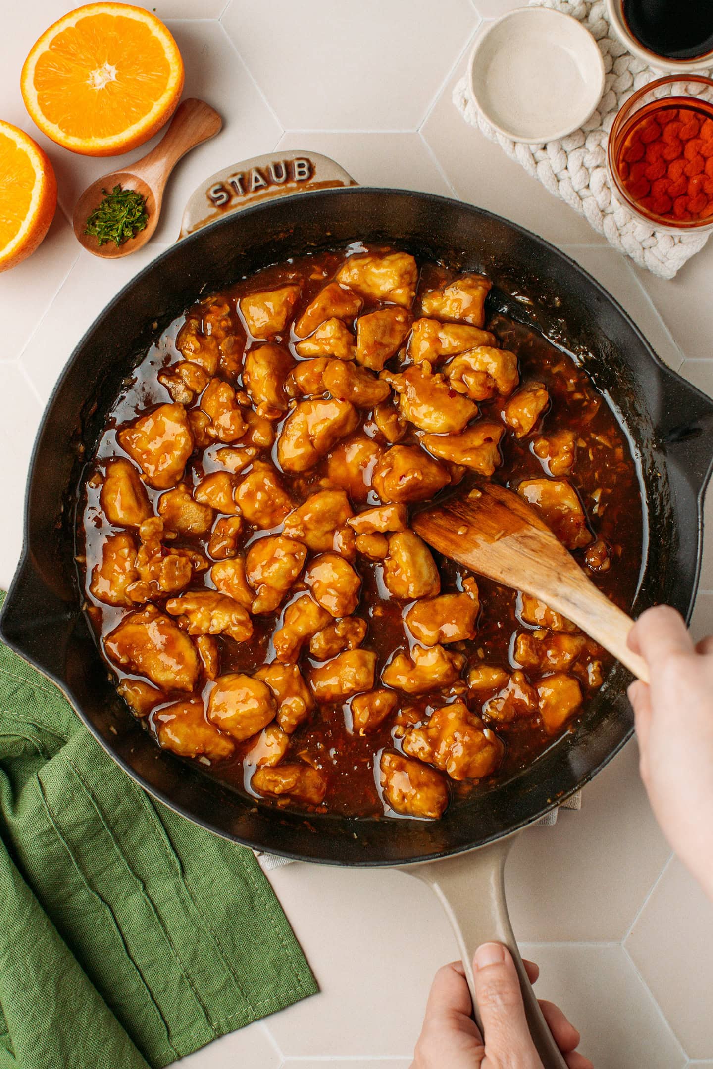 Tossing baked tofu with orange sauce in a skillet.