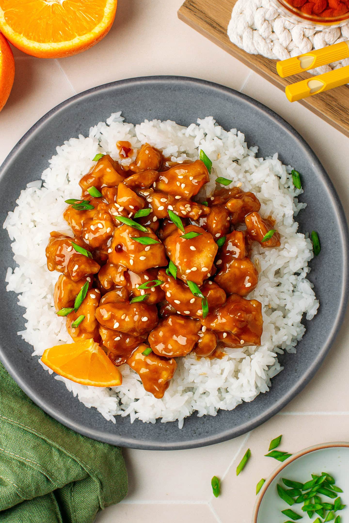 Plate filled with white rice, orange tofu, sesame seeds, and chopped green onions.