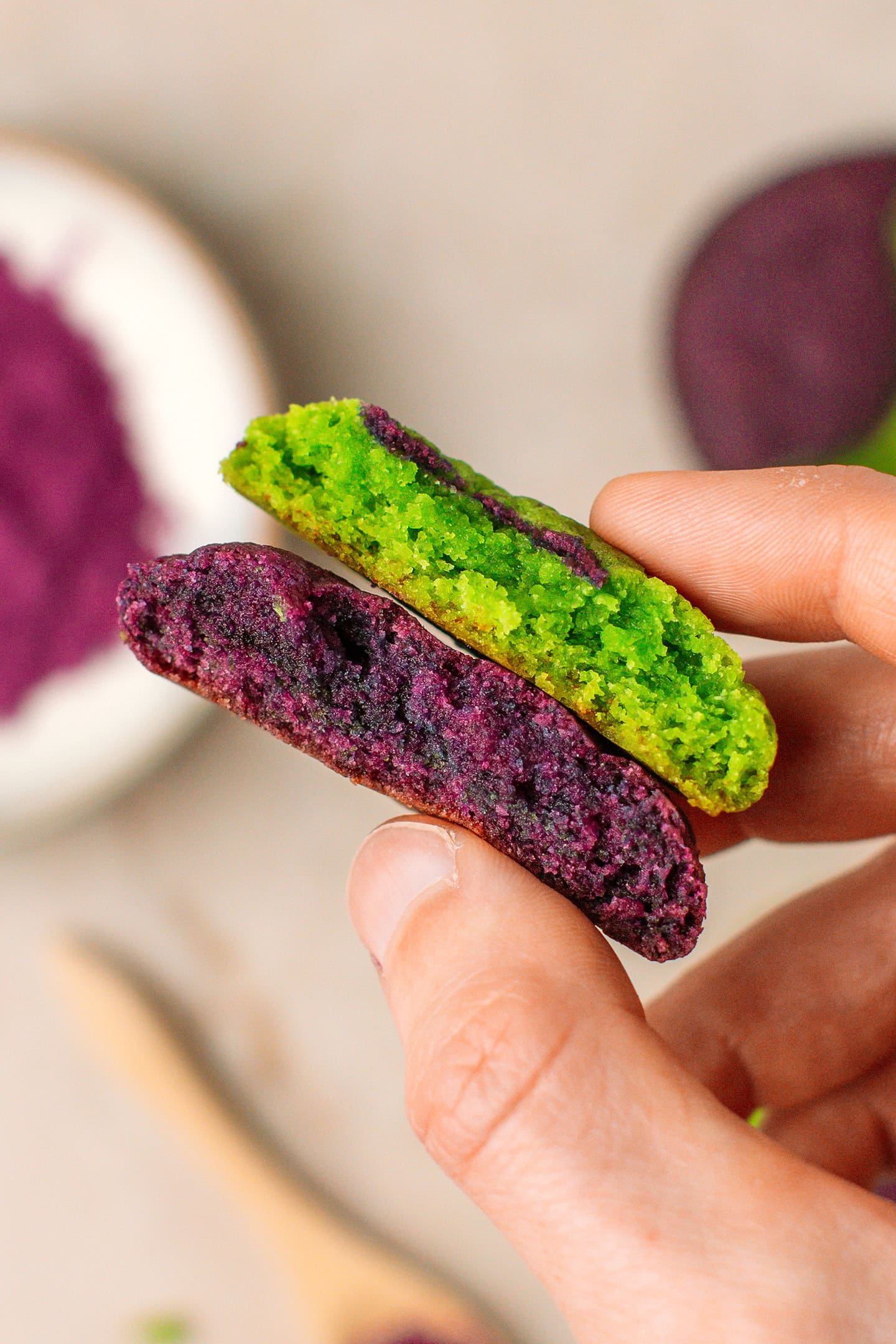 Holding an ube pandan cookie broke in half, revealing the chewy centers.